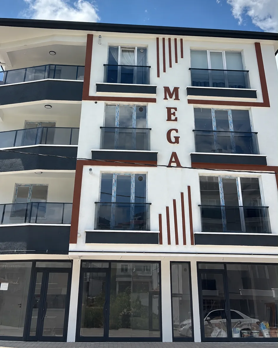 Mega Gümüş konut projesinin cam korkuluklu balkonları ve cephedeki bordo MEGA harfleri