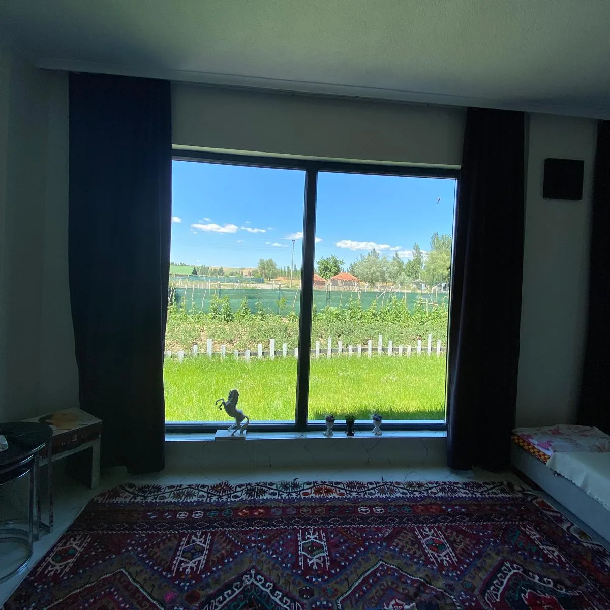 Salonun geniş penceresinden çim alan ve bahçe çiti
